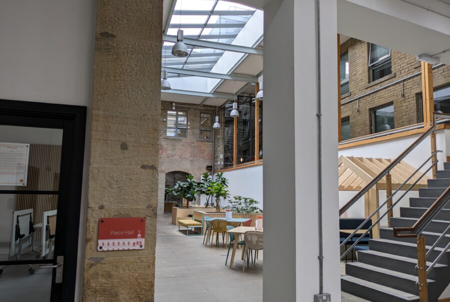 A clean and apparently freshly renovated building interior with tables and chairs and a sign that reads 'Piece Hall'.