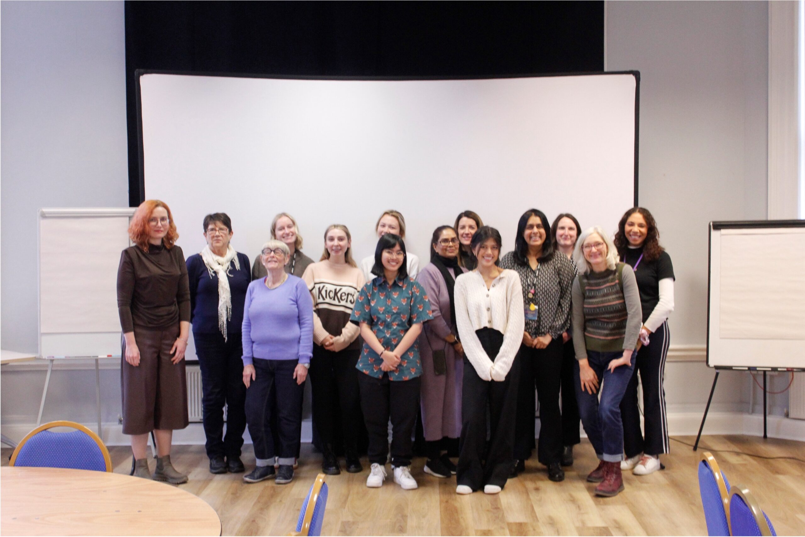 A group of women of different ages and ethnicities stand together smoking at the camera.