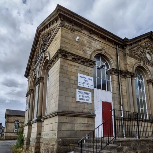 On a corner of the now dilapidated Queens Road Neighbour Centre, a sign reads 'Healthy Living Gym'.